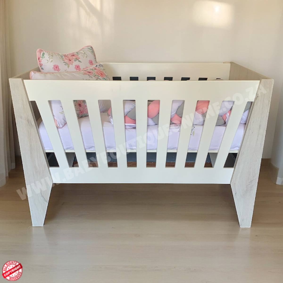 Emma Large Wooden Cot-White_NordicIce White crib with floral bedding on a wooden floor