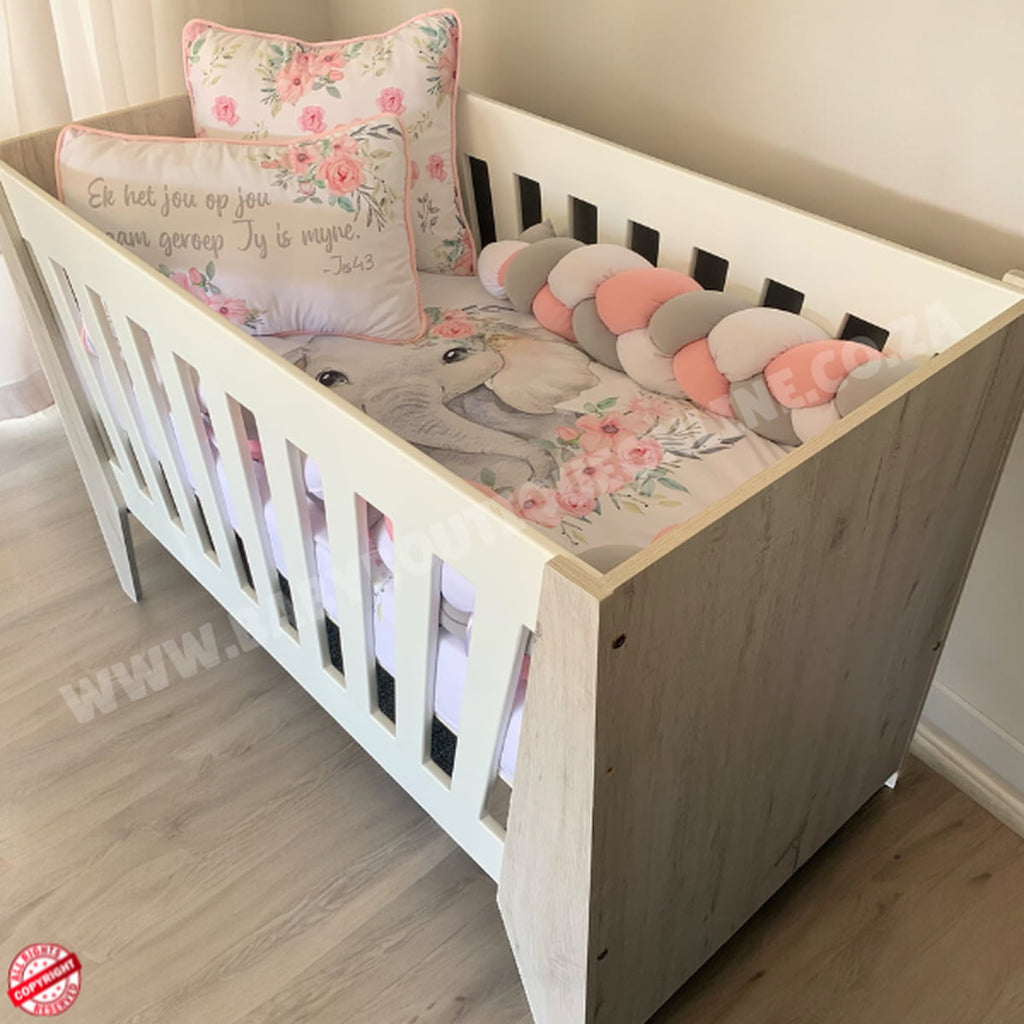Emma Large Wooden Cot-White_NordicIce White crib with floral bedding on a wooden floor