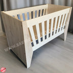 Emma Large Wooden Cot-White_NordicIce White crib with floral bedding on a wooden floor