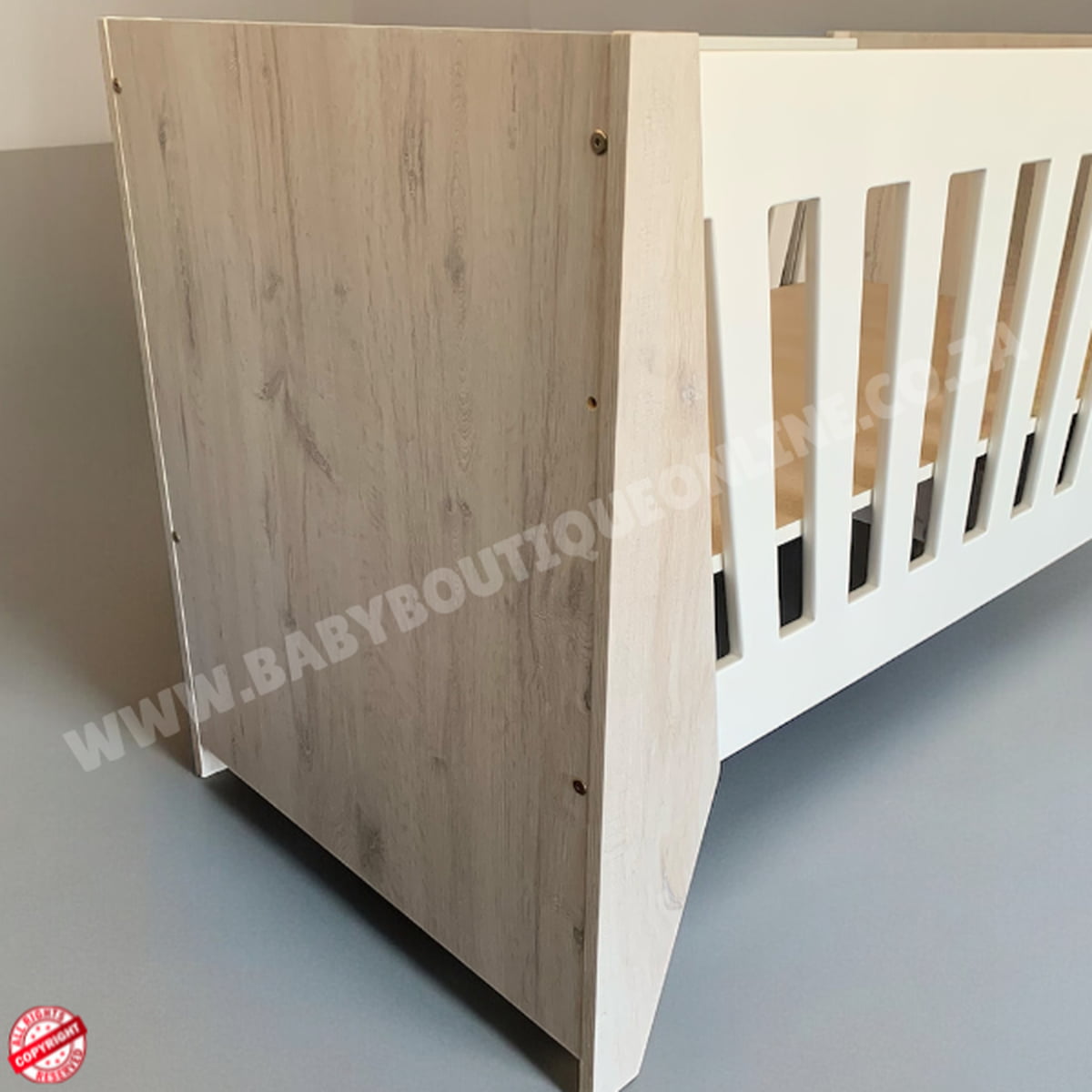 Emma Large Wooden Cot-White_NordicIce White crib with floral bedding on a wooden floor