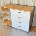 Wooden cabinet with white drawers and wooden top on a light wooden floor.
