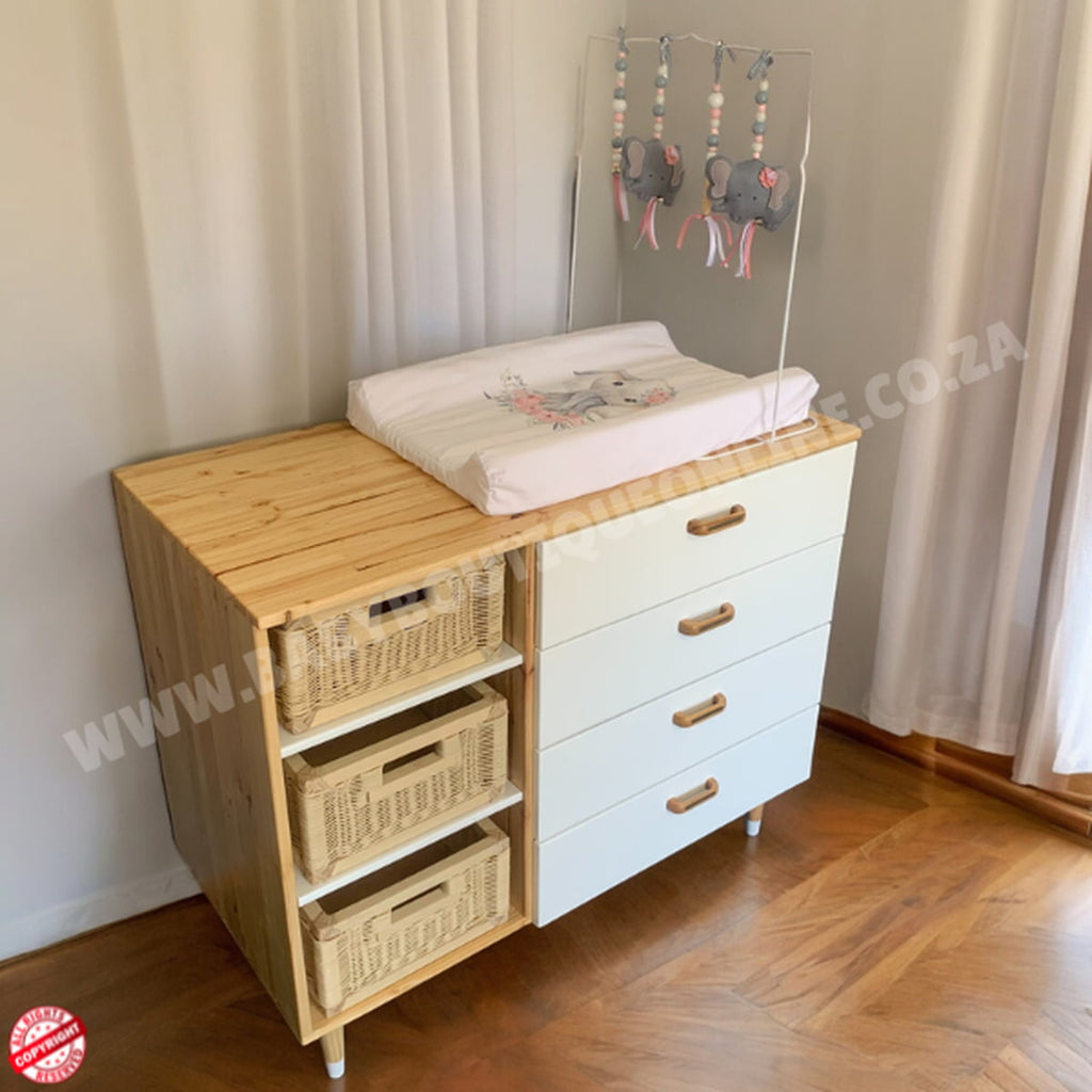 Wooden changing table with drawers and a white top in a room setting.