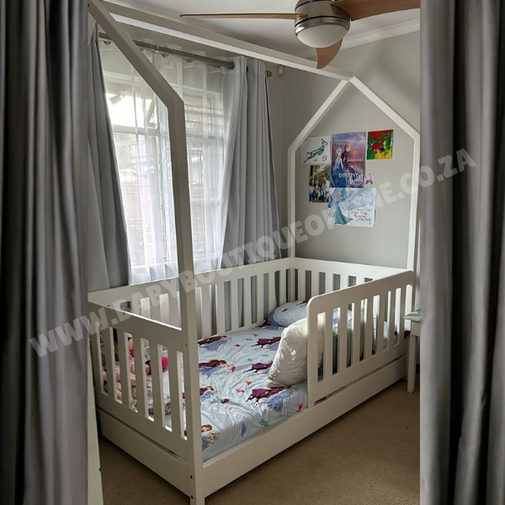 Children's room with a white crib and colorful bedding, curtains, and ceiling fan.
