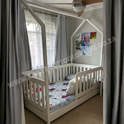 Children's room with a white crib and colorful bedding, curtains, and ceiling fan.