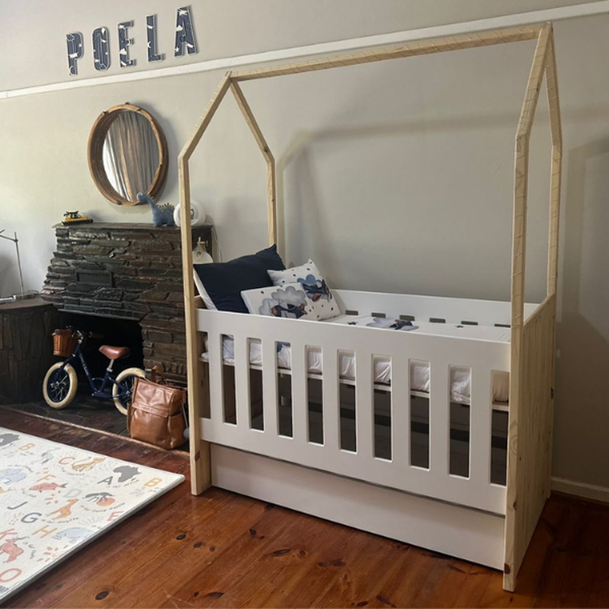 Tent Large Cot-White_OakSmoke with a house-shaped top in a room with a fireplace and toys.