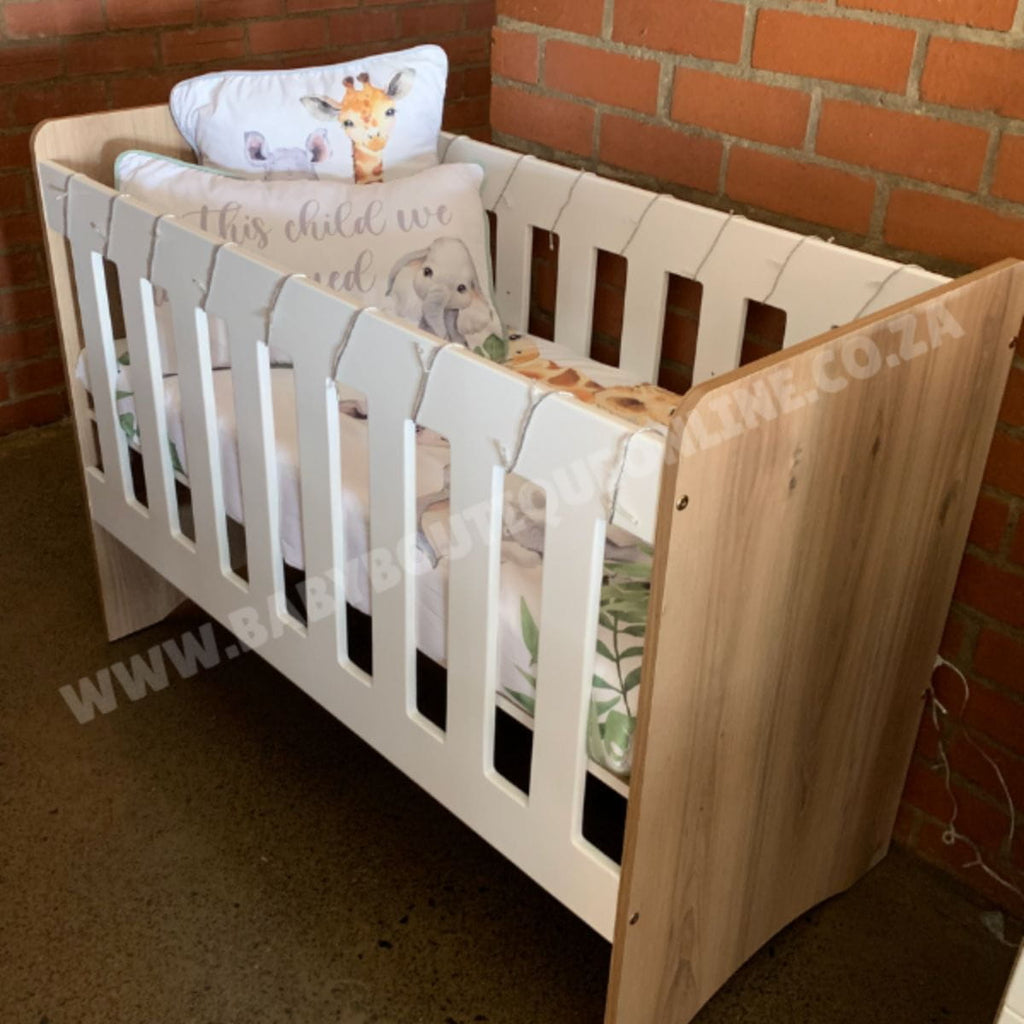 StandardCot-WhiteMDF_Sahara with baby bedding against a brick wall