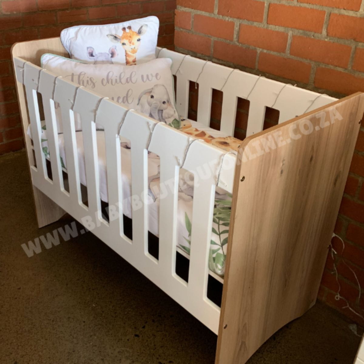 StandardCot-WhiteMDF_Sahara with baby bedding against a brick wall