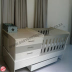 BabyBedroominaBox5-in-1Cot White crib with drawers in a room setting, featuring 'Baby Boutique' branding.