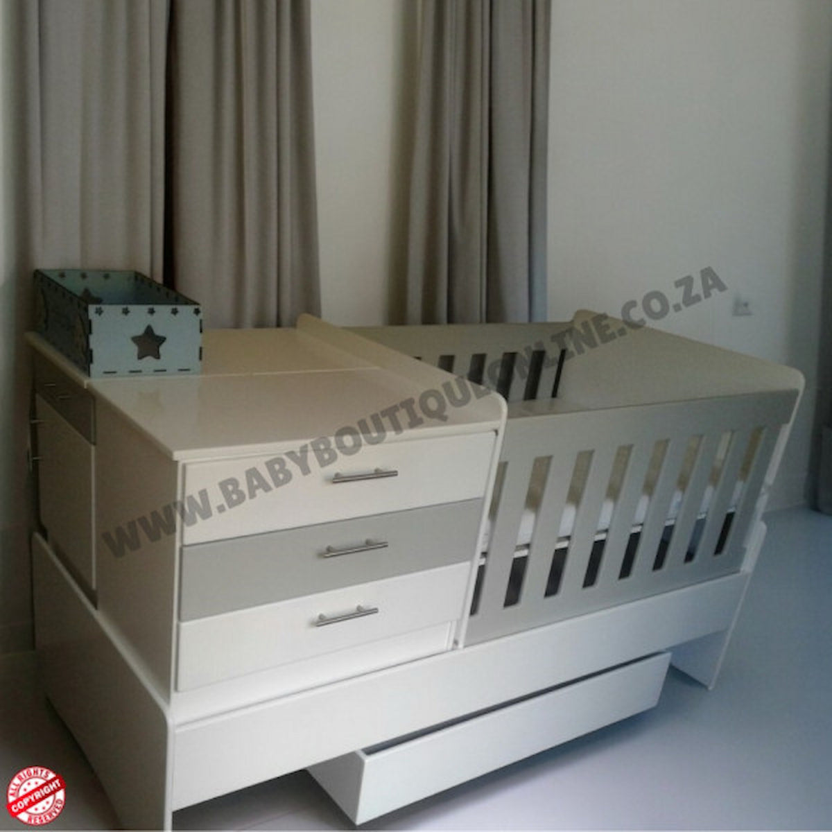 BabyBedroominaBox5-in-1Cot White crib with drawers in a room setting, featuring 'Baby Boutique' branding.
