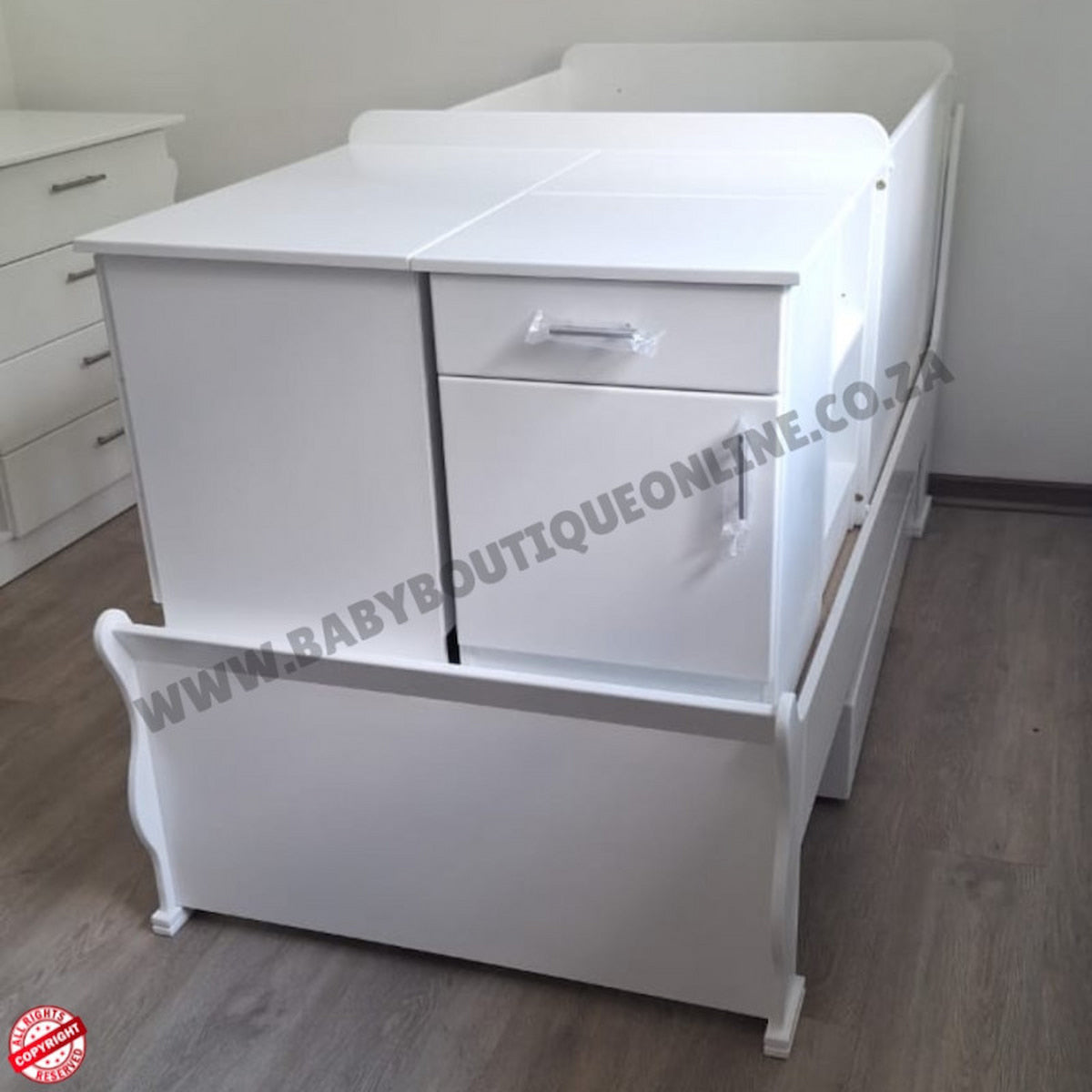 BabyBedroominabox5-in-1SleighCot White baby crib with drawers on a wooden floor, branded 'Baby Boutique Online'.