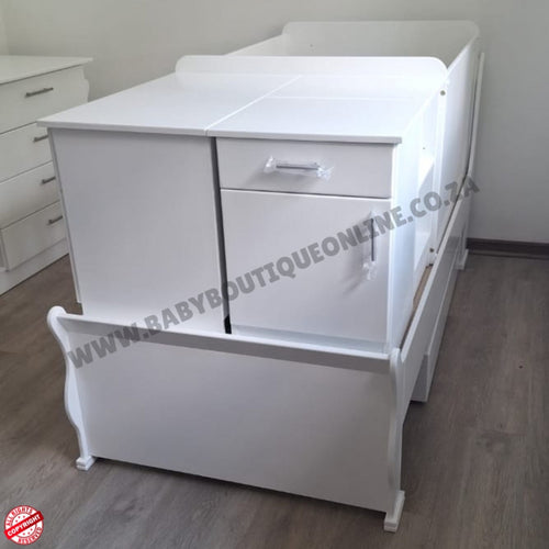 BabyBedroominabox5-in-1SleighCot White baby crib with drawers on a wooden floor, branded 'Baby Boutique Online'.