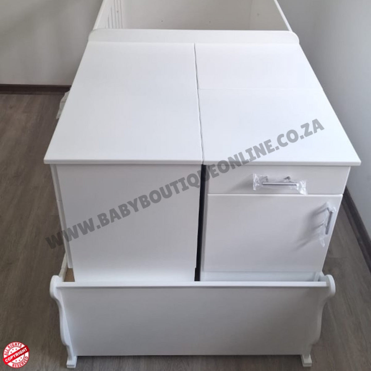 BabyBedroominabox5-in-1SleighCot White baby changing table with drawers on a wooden floor.