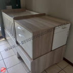 BabyBedroominaBox5-in-1Cot Wooden crib with white mattress on a tiled floor, branded 'Baby Boutique Online'.