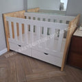 Large Cot-Pine White crib with wooden sides in a room with a wooden floor and dresser.