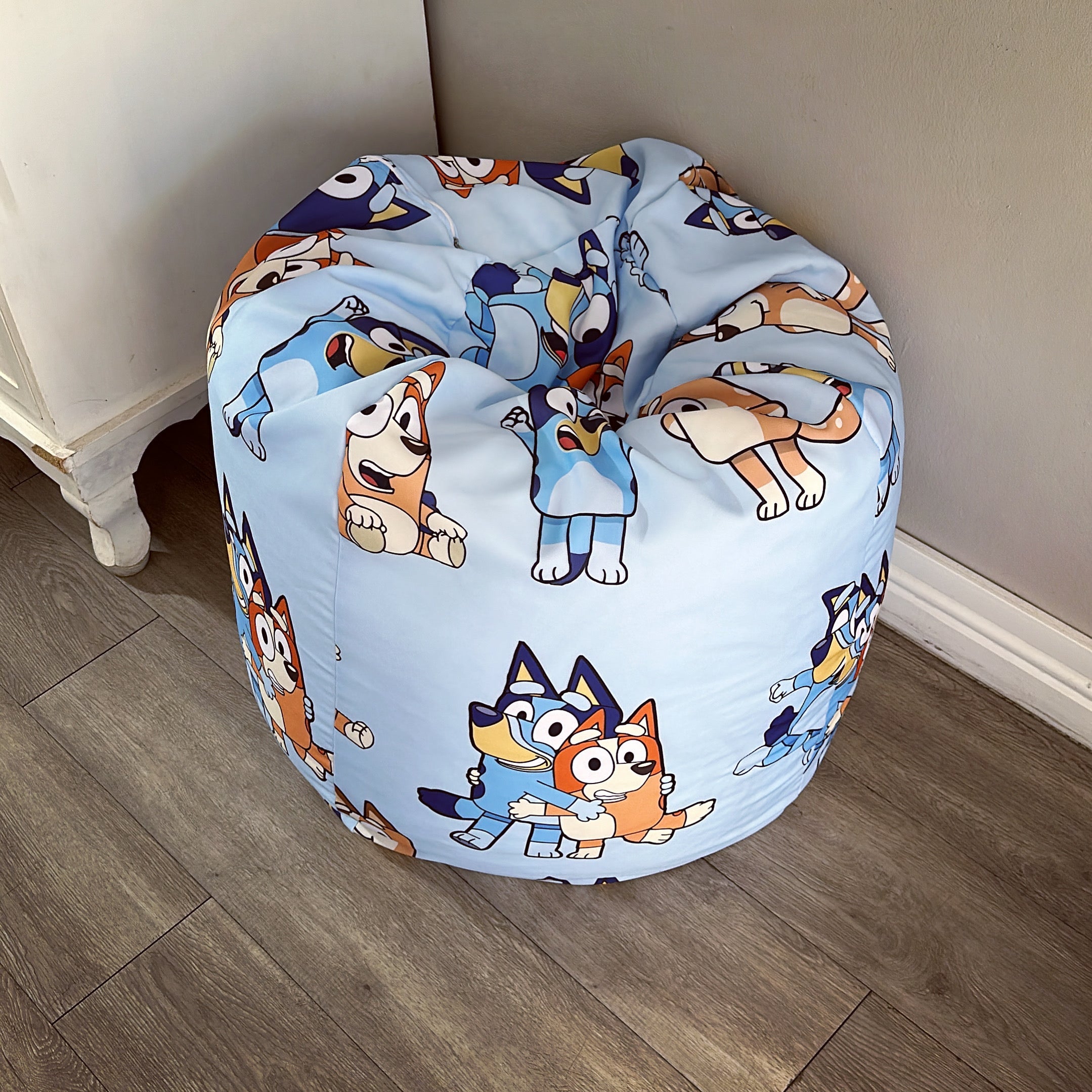 A round beanbag chair with a printed design featuring cartoon characters on a blue background.
