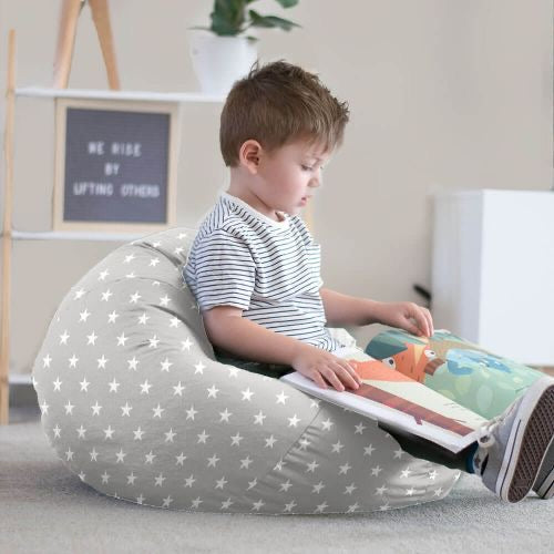 Child sitting on a star-patterned bean bag reading a book in a cozy room.