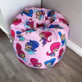 A pink beanbag chair with printed characters from Shimmer & Shine children's show, featuring designs with the characters Shimmer, Shine, and their friends.