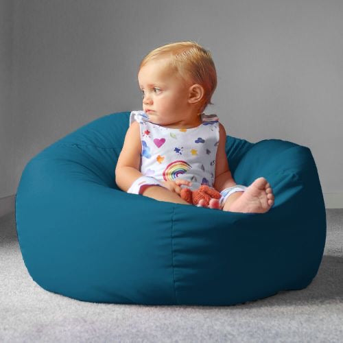 Child sitting on a teal bean bag with a gray background