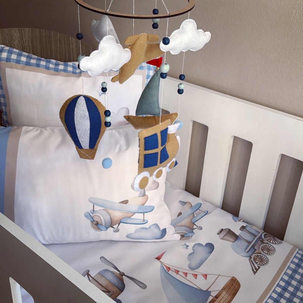 Children's crib with airplane-themed bedding and mobile