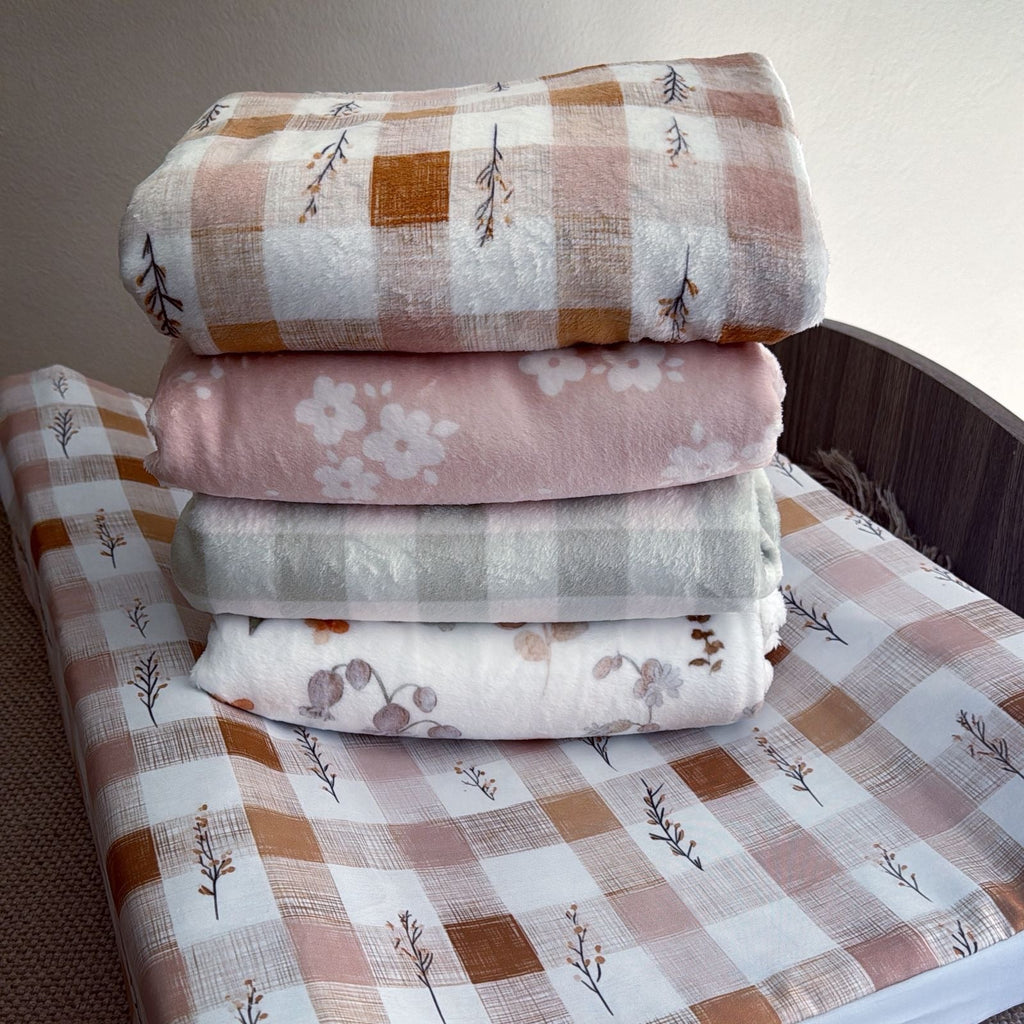 Stack of folded fabric sheets with patterns on a wooden surface.
