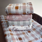 Stack of folded fabric sheets with patterns on a wooden surface.