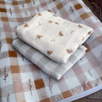 Stack of folded fabric sheets with bird pattern on a checkered fabric background