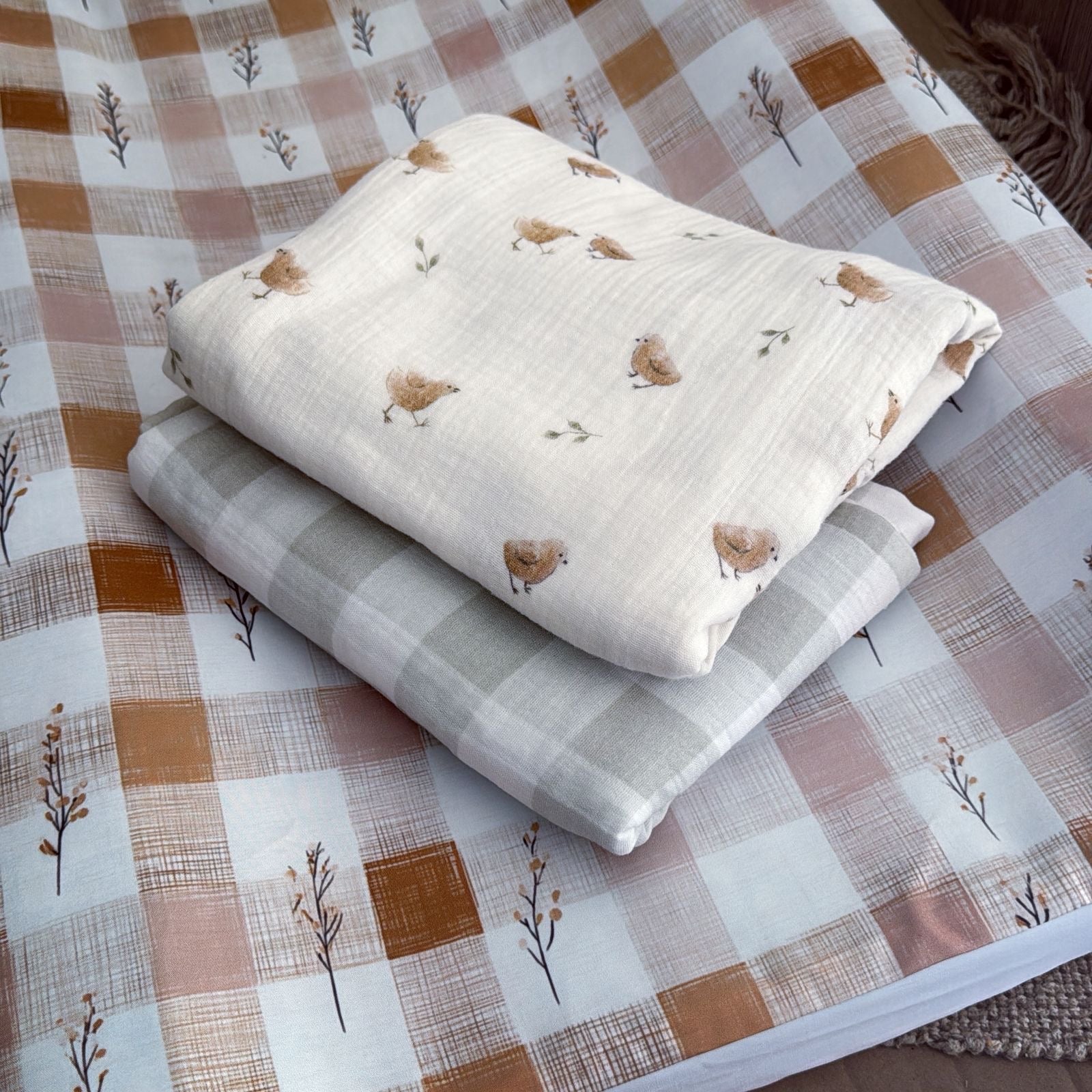 Stack of folded fabric sheets with bird pattern on a checkered fabric background
