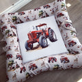 A square farm-themed pet bed with a white background and a printed border of red tractors, cows, sheep, barns, and trees, featuring a large central white square patch with a red tractor illustration.