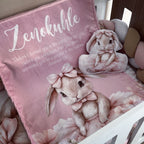Pink pillow with bunny design and text on a bed