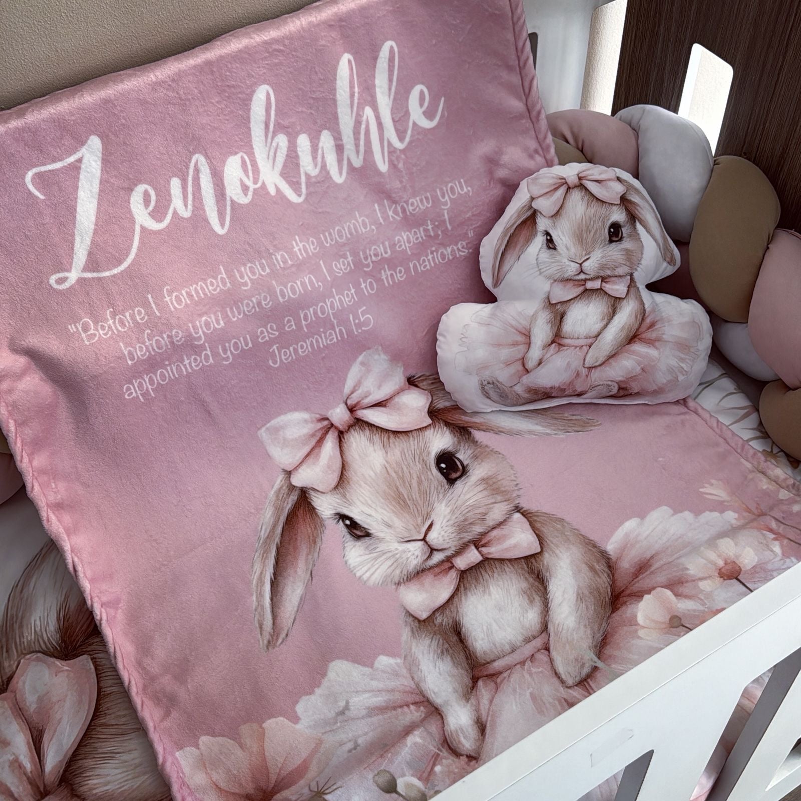 Pink pillow with bunny design and text on a bed