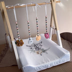 Baby play mat with butterfly design and hanging toys on a wooden frame