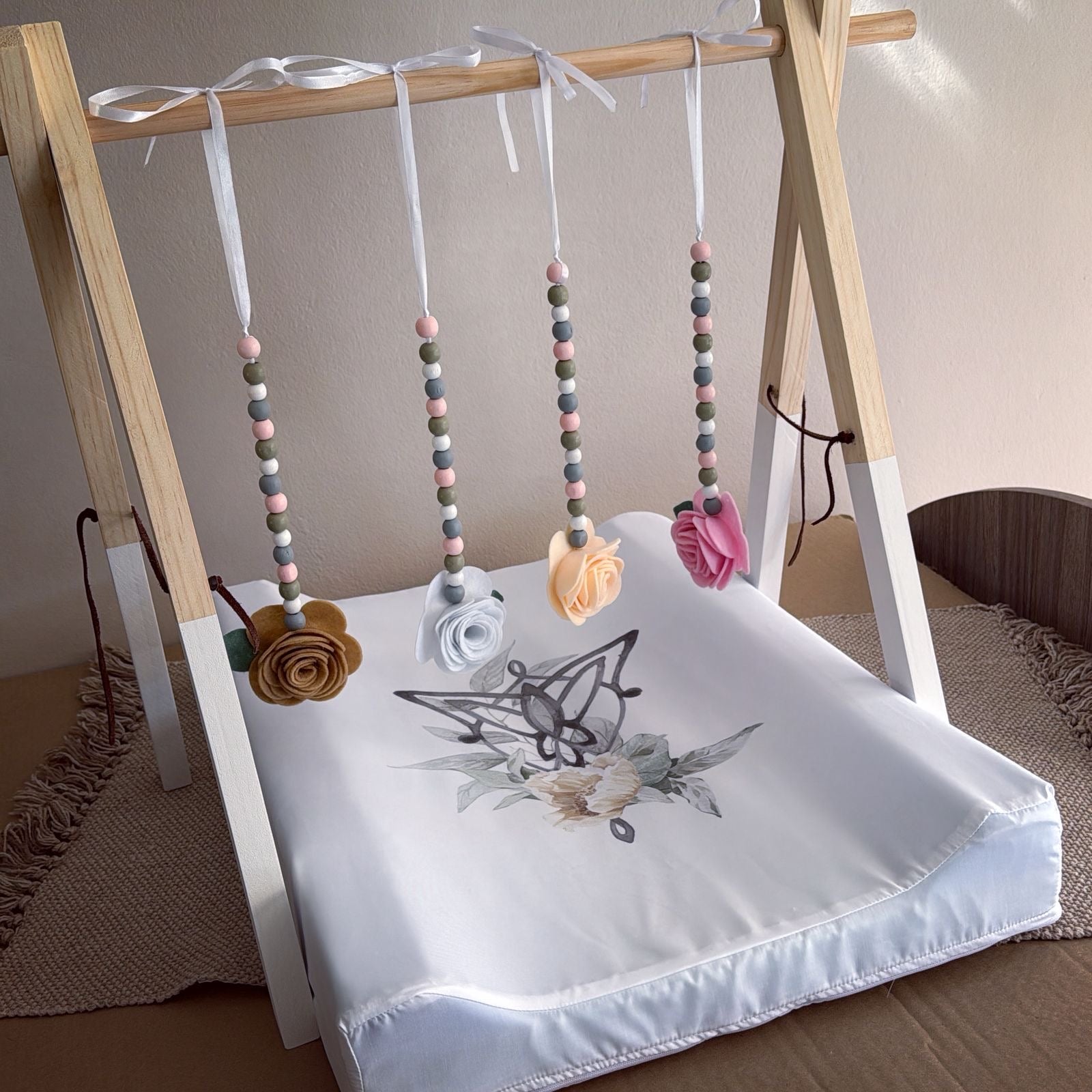 Baby play mat with butterfly design and hanging toys on a wooden frame