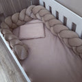 A baby crib bedding set featuring a stone fitted sheet, a matching pillow, and a thick braided bumper pad in a taupe-beige color, shown from an overhead angle.