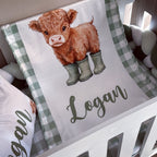 Crib sheet with a cow illustration and 'Logan' text on a checkered pattern