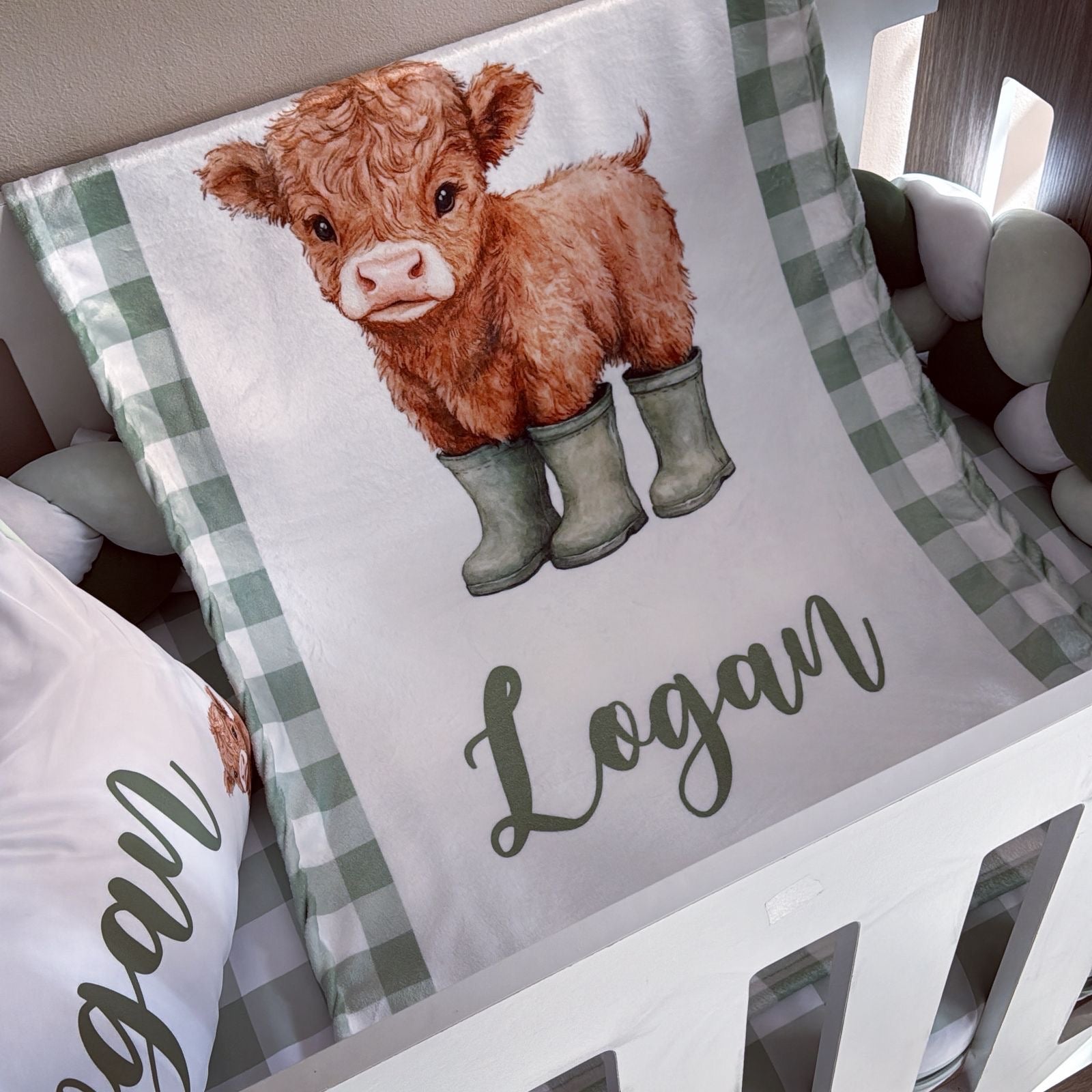 Crib sheet with a cow illustration and 'Logan' text on a checkered pattern