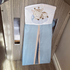 Baby crib with a blue sheet and a pillow with a giraffe design in a wooden crib.