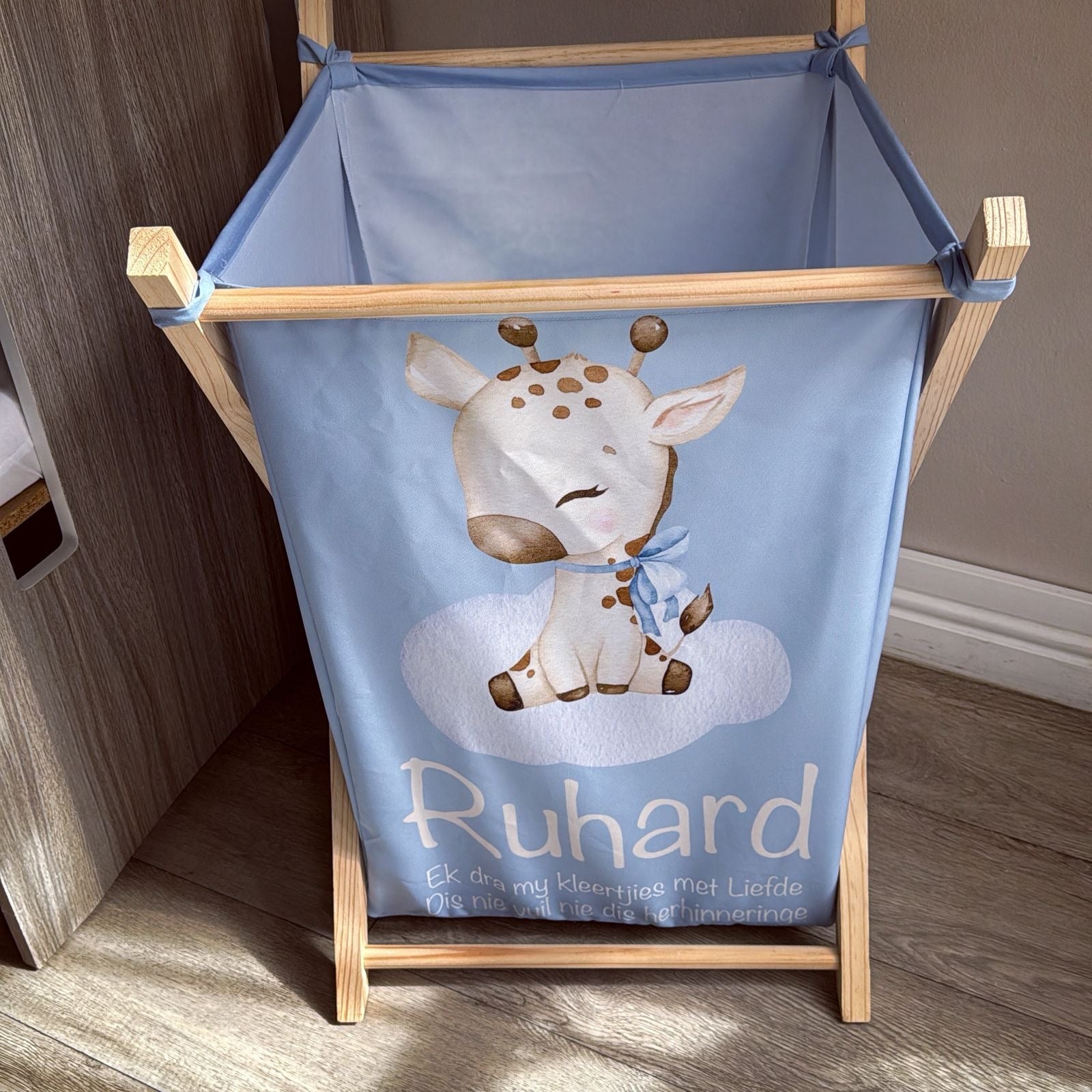 Children's laundry basket with a giraffe design and 'Ruhard' branding on a wooden stand.