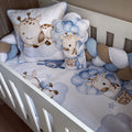 Baby crib with blue and brown giraffe-themed bedding and pillows.