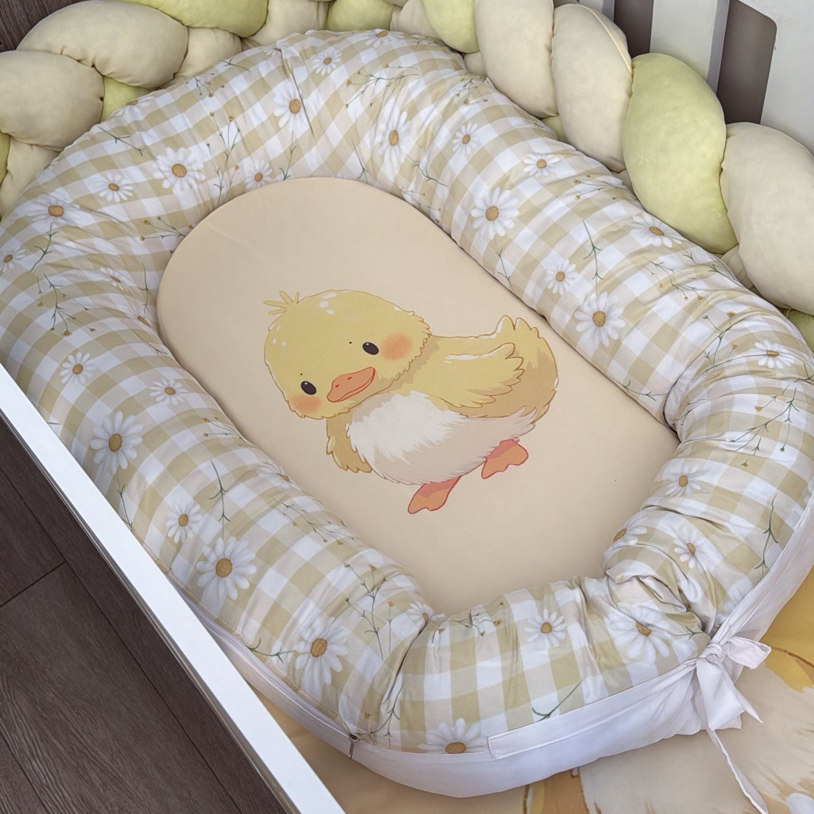 Baby nest with a cartoon duck design on a wooden floor