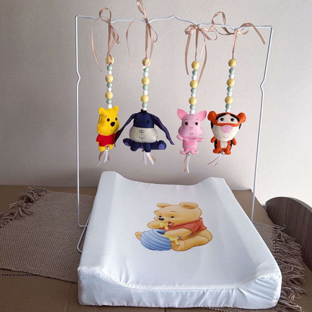 Baby crib mobile with cartoon characters above a changing table with a similar design.