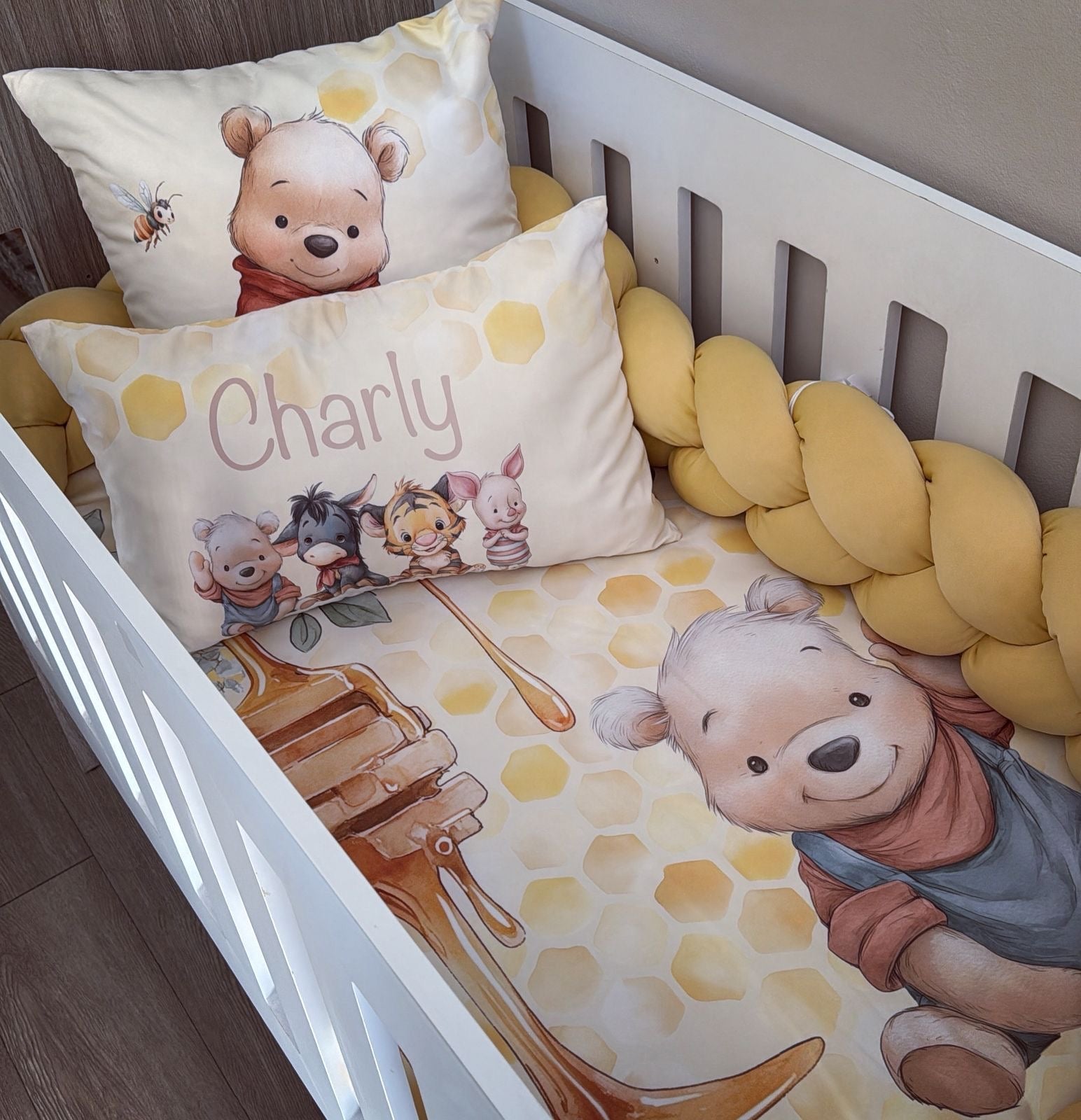 Nursery crib with Winnie the Pooh-themed bedding and pillows.