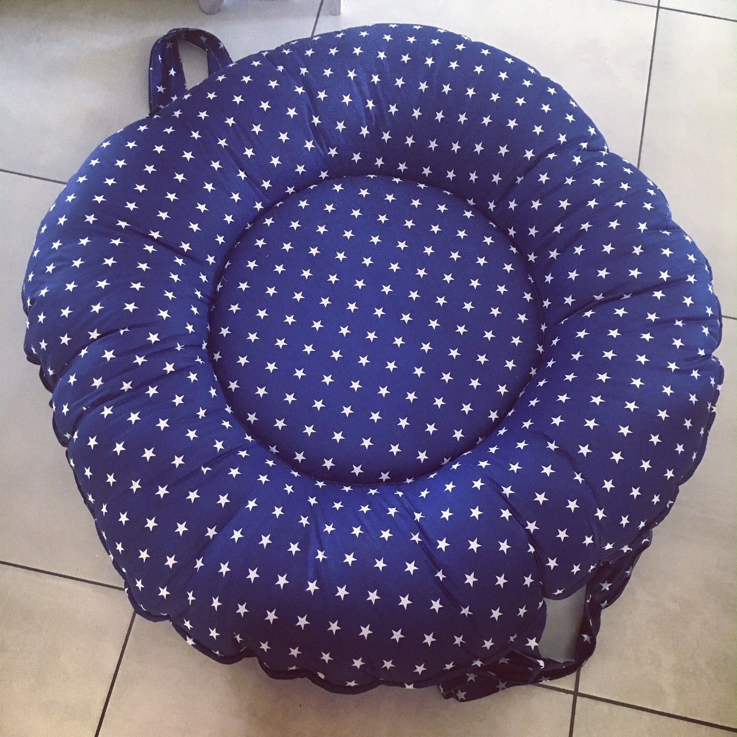 Blue cushion with white star pattern on a tiled floor
