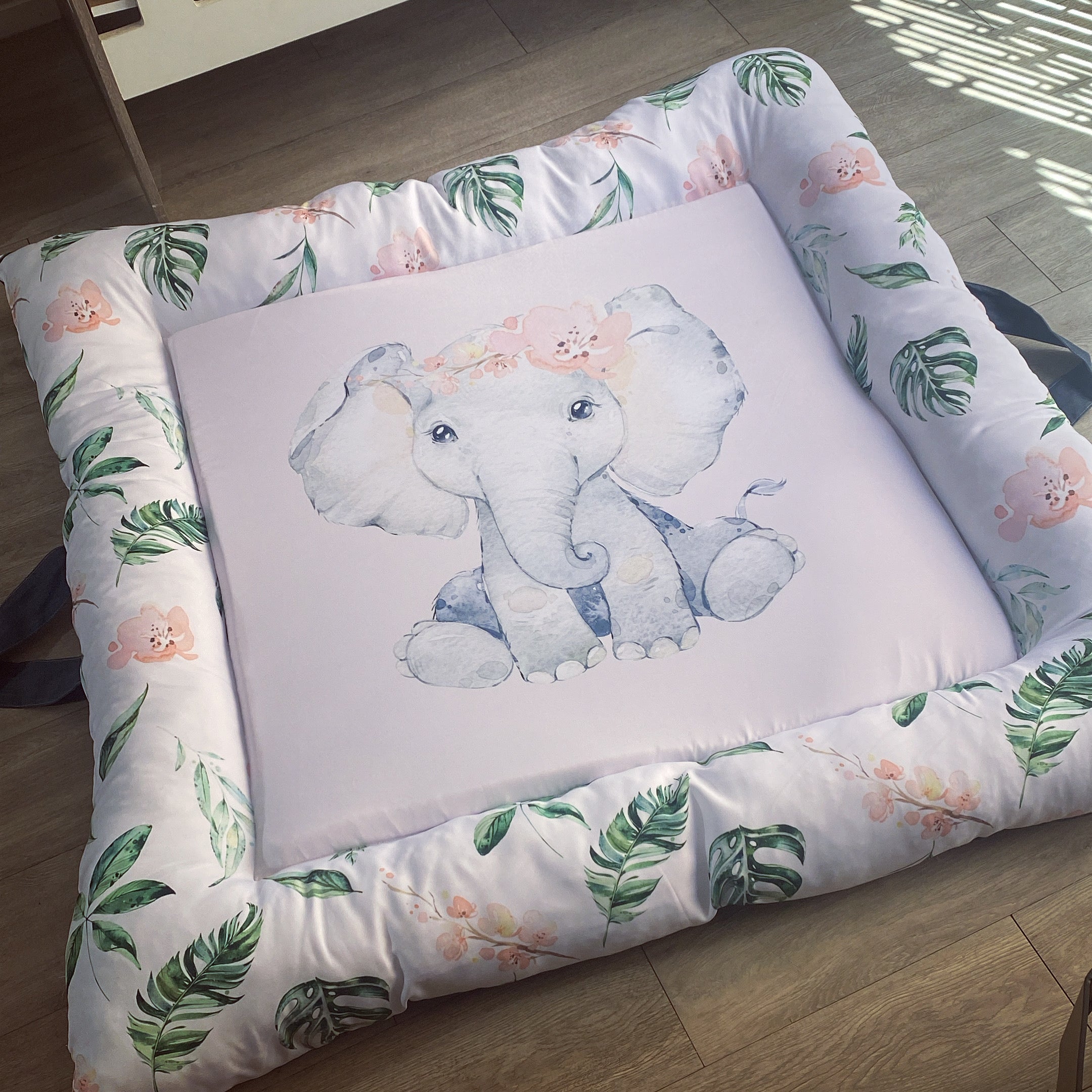 A soft play doughnut with an illustration of an elephant in the center, surrounded by green leaves and a pink floral border.