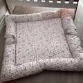 Floral-patterned crib bumper on a wooden floor