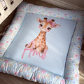 A square baby pet bed with a light blue center featuring a watercolor giraffe and the name 'Ame' in pink script, surrounded by a floral-patterned border.