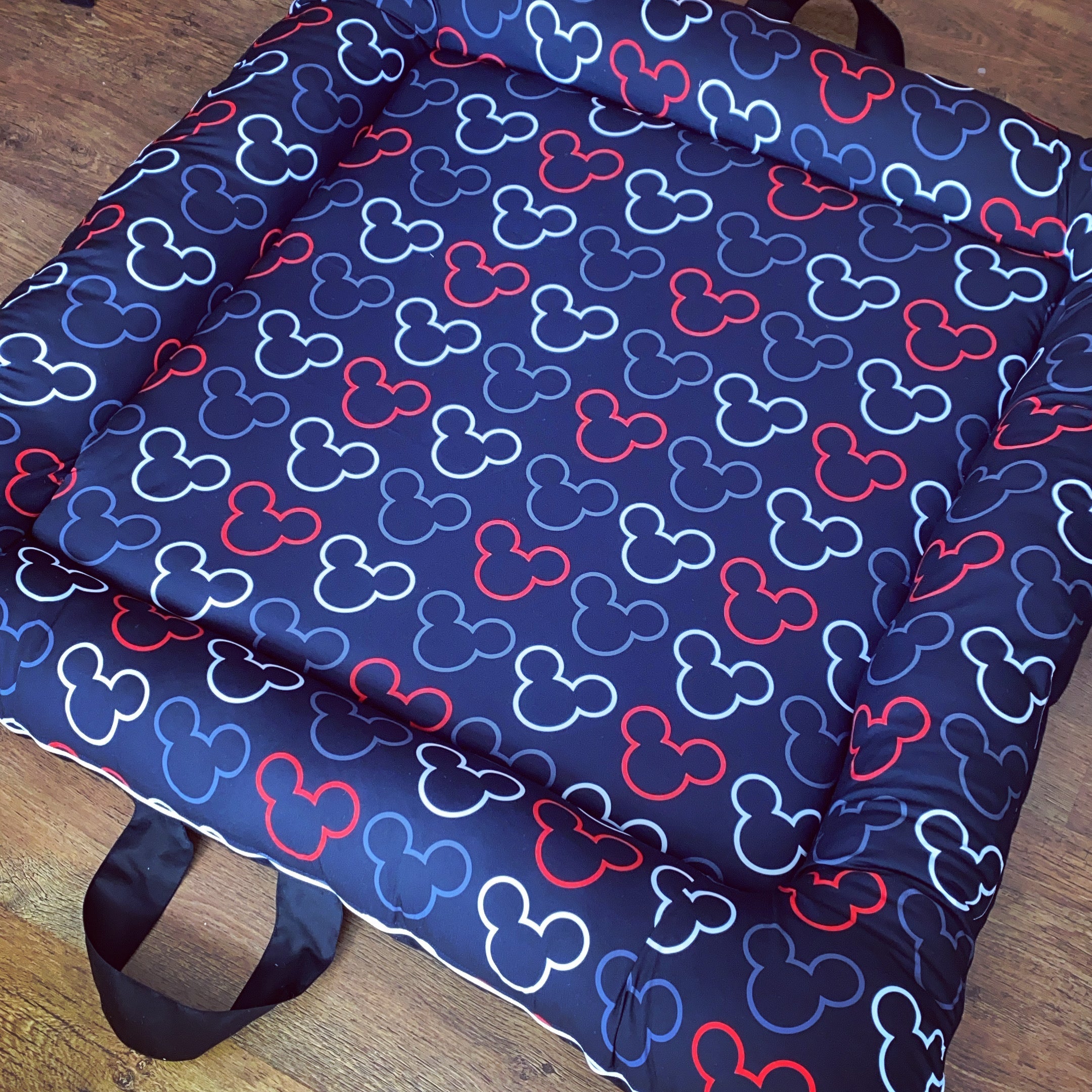 A soft play doughnut with a Mickey Mouse pattern in blue, red, and black, featuring a carry handle.