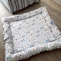 Patterned doughnut bed on a wooden floor with a striped rug in the background