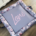 A gray baby play doughnut with a floral pattern around the edge and the name 'Lana' written in the center.