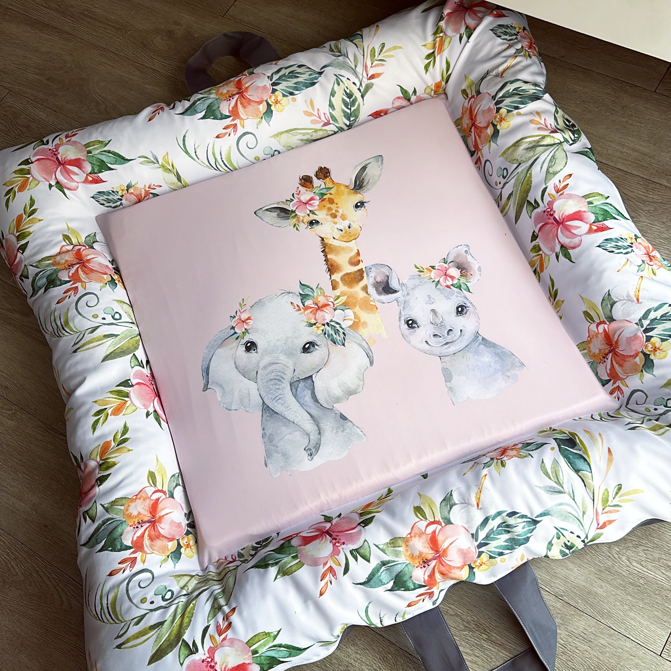 A pink play doughnut with a floral pattern and illustrations of an elephant and a giraffe in the center.