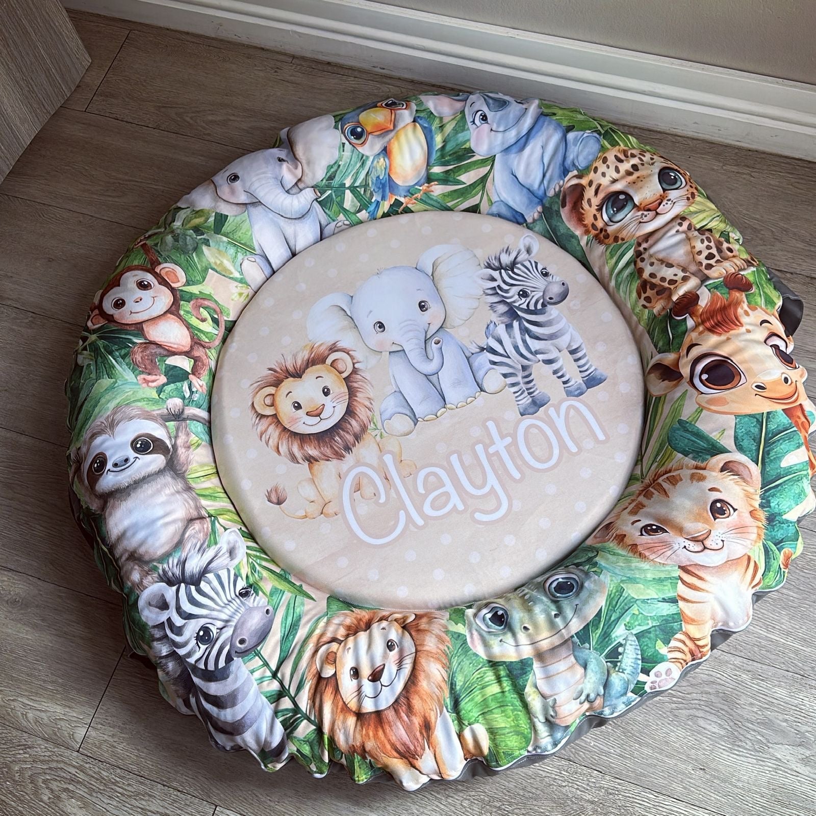 Doughnut - Stone Safari 01 with animal prints and 'Clayton' embroidery on a wooden floor.